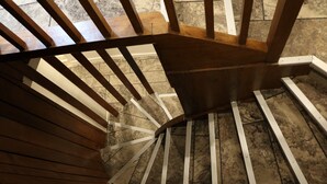 Una escalera de madera con barandas blancas y piso de concreto.