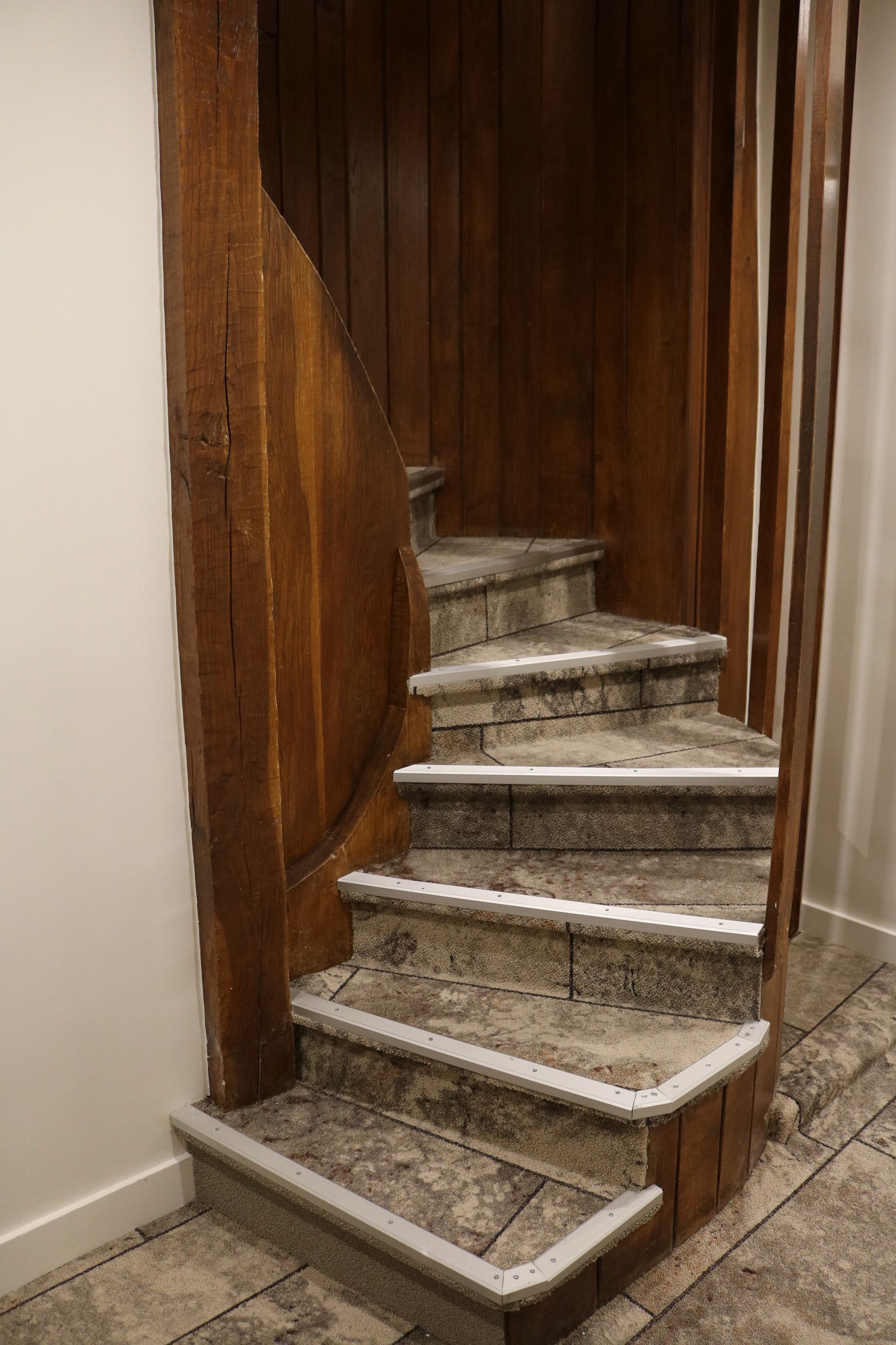 Un escalier en colimaçon avec des rampes en bois et des marches en pierre.