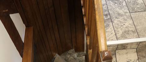 A wooden staircase with metal handrails and a tiled floor.