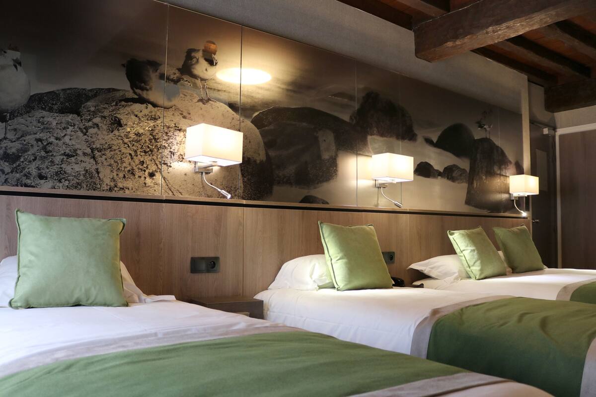 Ein Hotelzimmer mit zwei Betten, grüner Bettwäsche, einem großen Wandbild und Nachttischlampen.