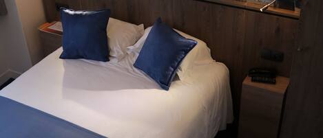 A hotel room with a large bed, two bedside lamps, a nightstand, and a decorative wall mural.