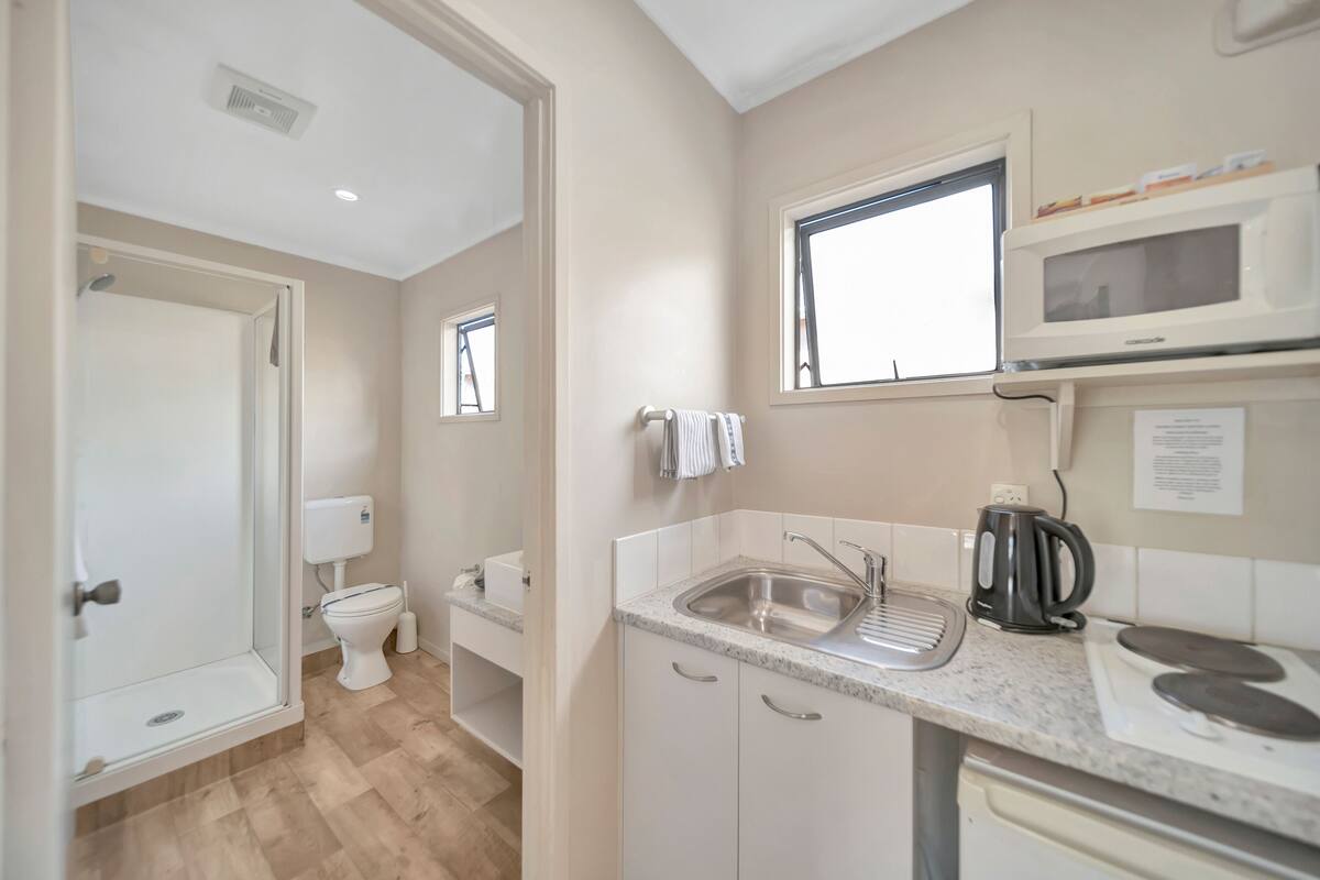 Cocina compacta con microondas integrado, un lavabo y un hervidor.
