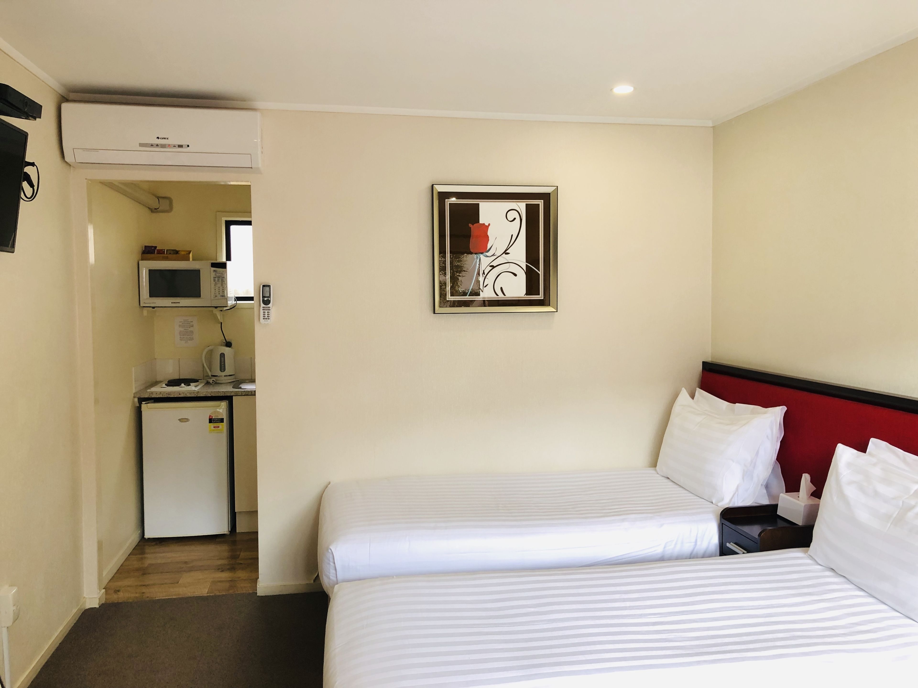 A hotel room with two beds, a kitchenette, and a microwave.