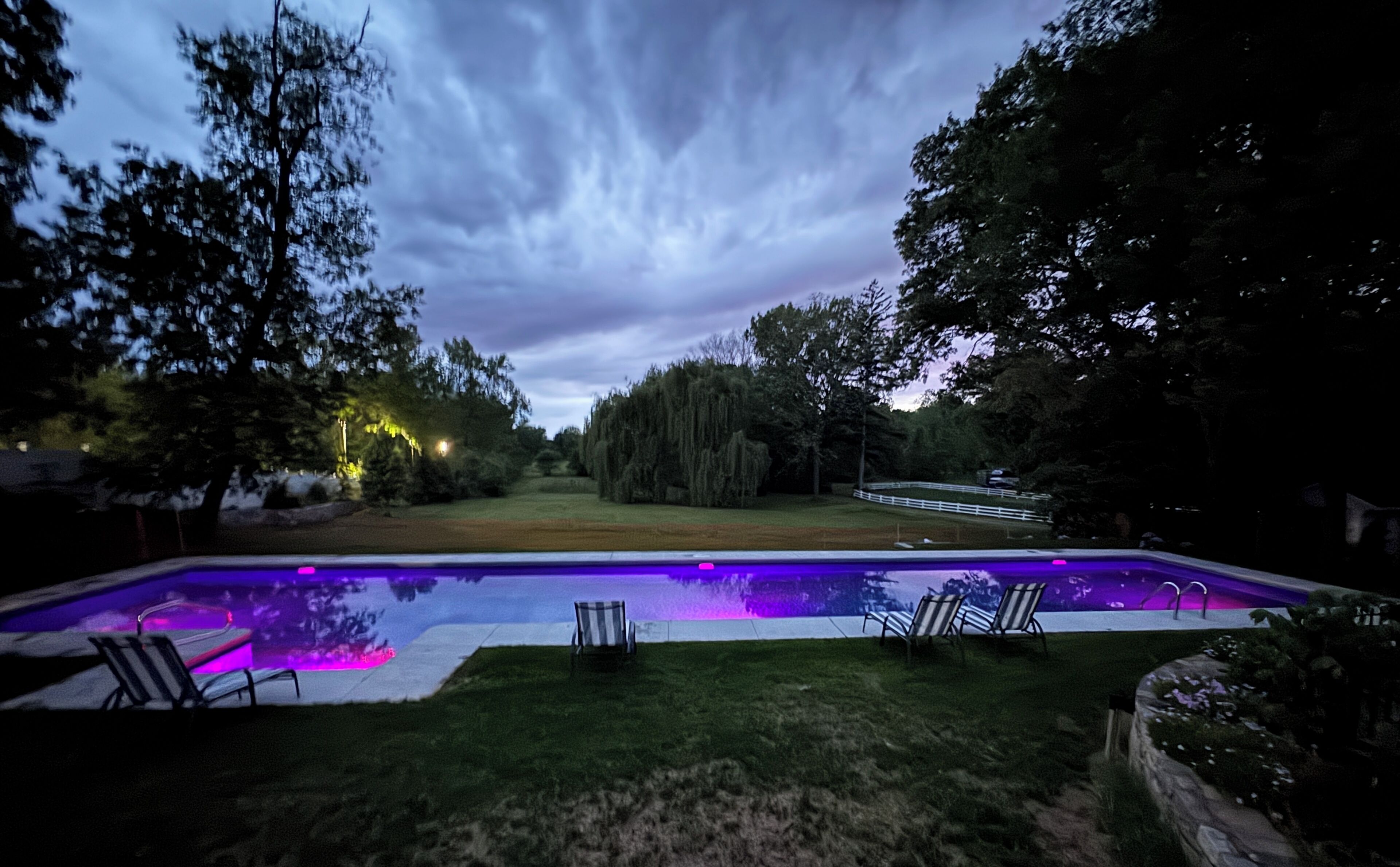 A swimming pool with a view of trees and a cloudy sky.