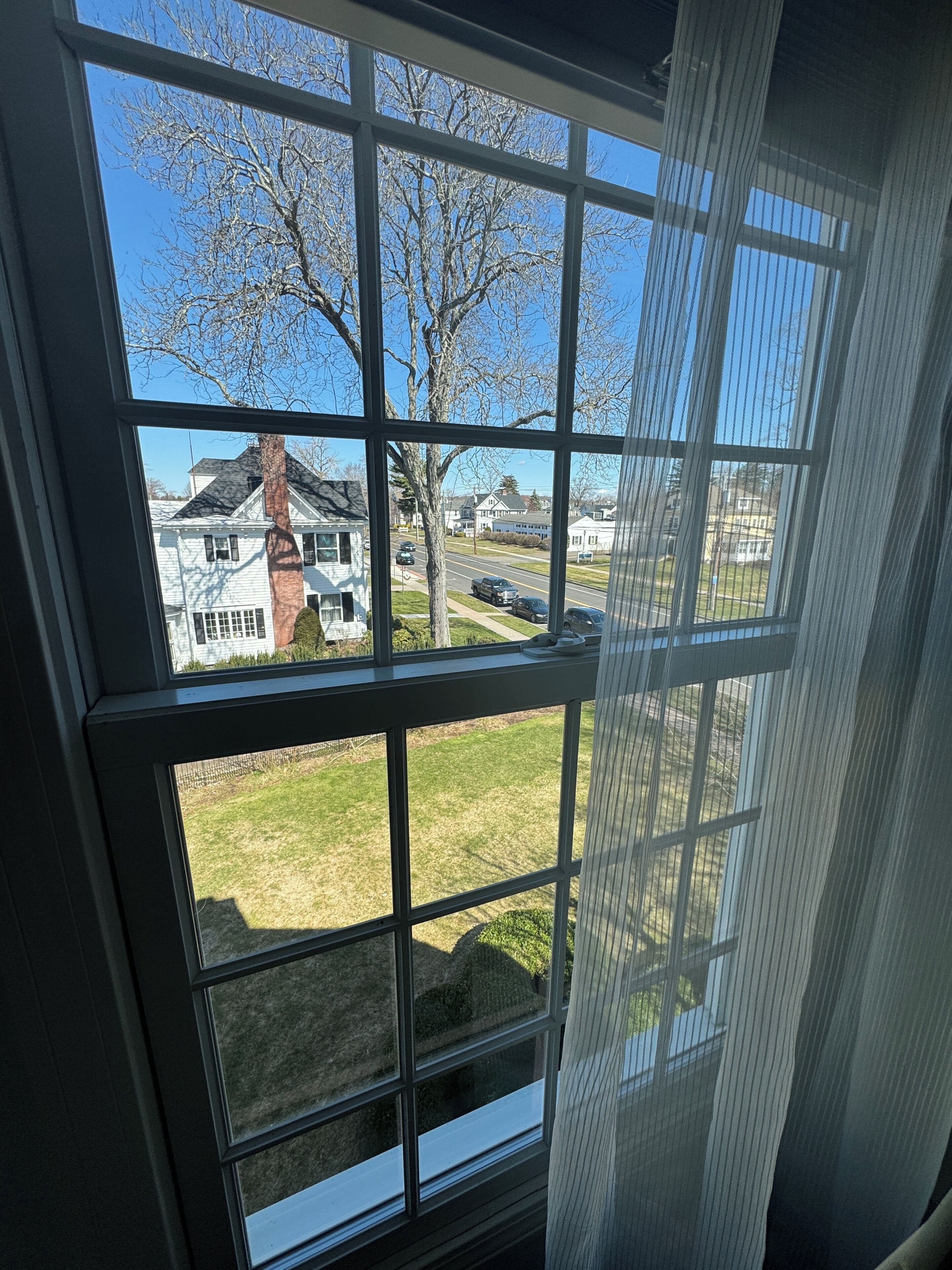 Una ventana con vistas a una zona residencial, con casas y una calle.