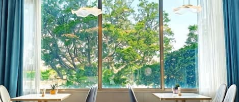 A room with a large window, two tables, and chairs.
