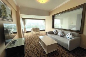 Sala de estar com sofá, mesa de centro e televisão. Tem uma varanda com vista para a cidade.
