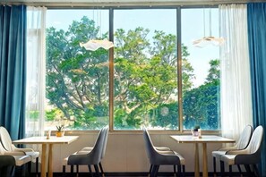 A room with a large window, two tables, and four chairs.