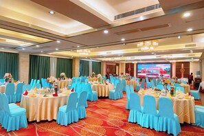 Un salón de banquetes con mesas redondas, sillas azules y centros de mesa florales.