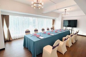 Una sala de conferències amb una taula llarga, cadires, plomes de noms i una pantalla de televisió.