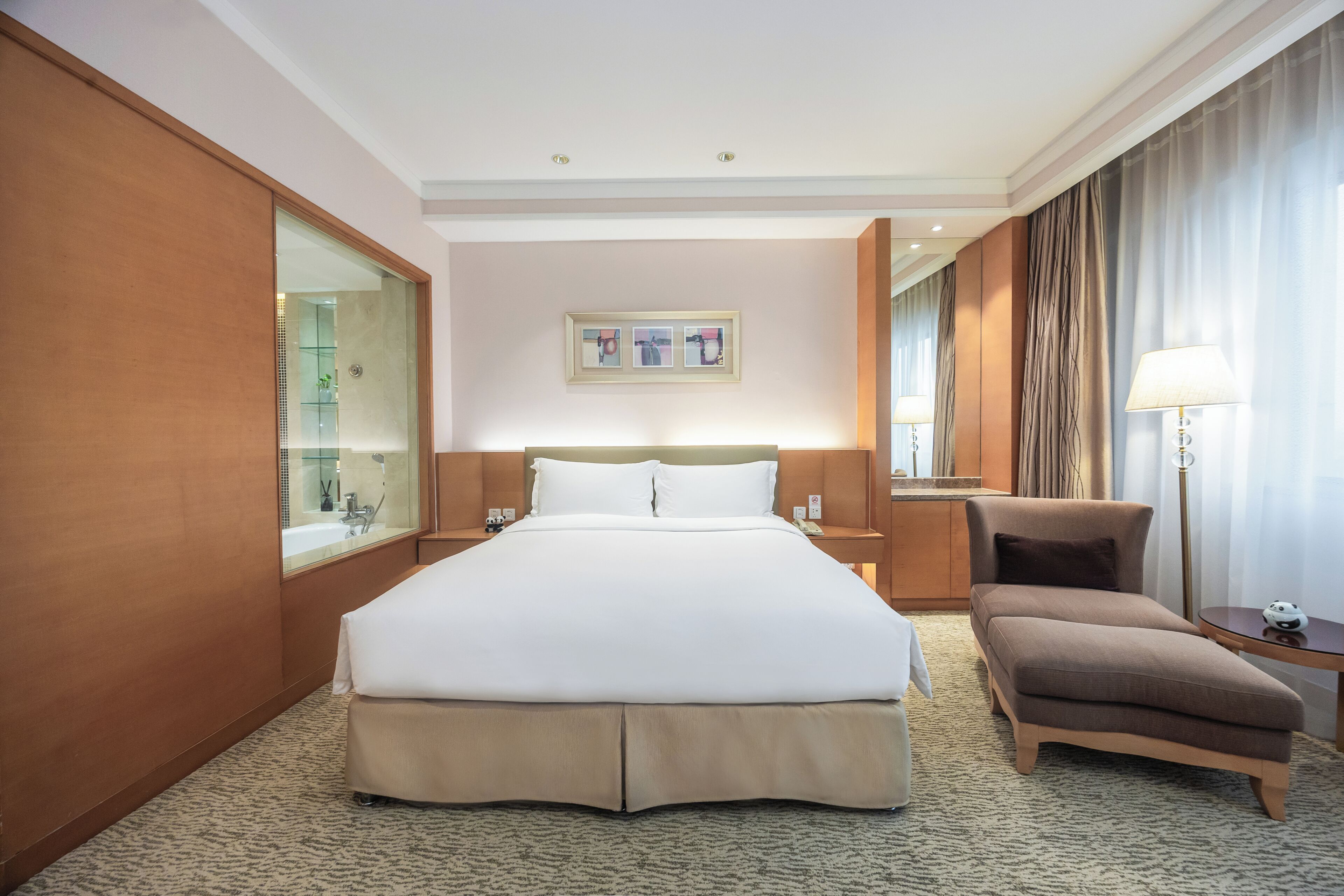 A hotel room with a large bed, a chair, a desk, a mirror, and a picture on the wall.