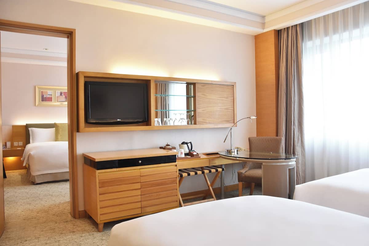 Una habitación de hotel con cama, escritorio con silla, televisor y minibar.
