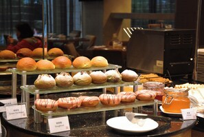 Una vetrina di panetteria con diversi prodotti da forno e un angolo dedicato al caffè.