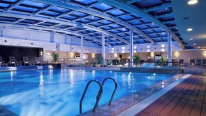 An indoor swimming pool with a glass ceiling, lounge chairs, and a reception area. - Millennium Hotel Chengdu (Chengdu)