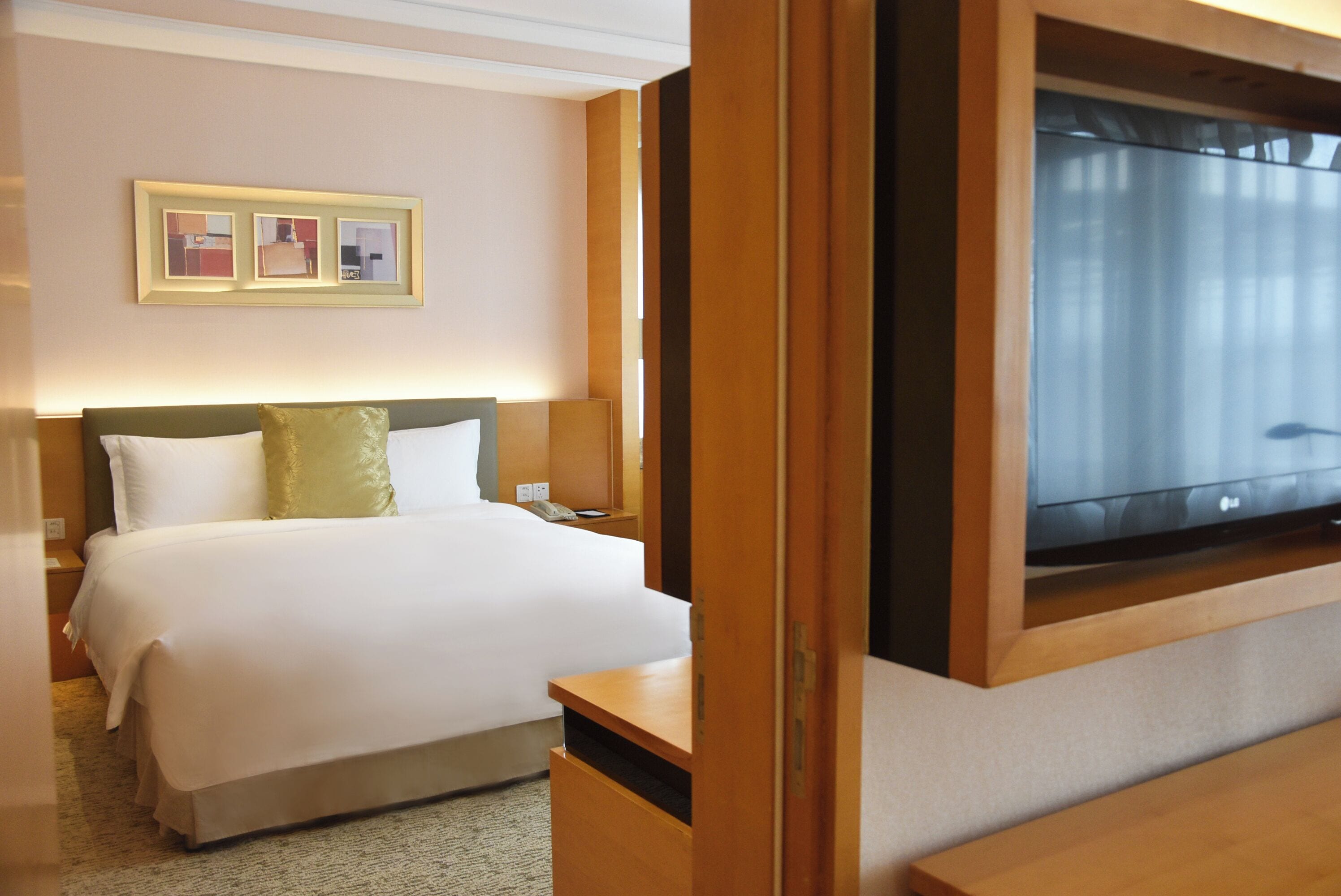 Una habitación de hotel con una cama, un televisor y un cuadro en la pared.