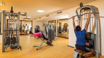 Een fitnessruimte met diverse trainingsapparaten, waaronder een pull-up bar en een leg press.