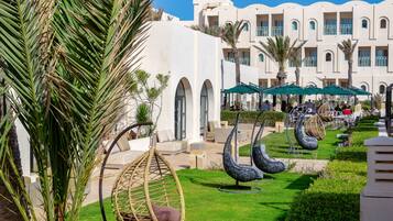 Un resort con sillones colgantes, mobiliario exterior y zona de piscina.