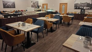 A restaurant with tables and chairs, a counter with a display case, and a chandelier.