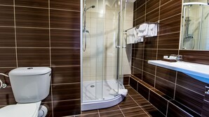 A modern bathroom with a glass-enclosed shower, a toilet, and a sink with a mirror above it.