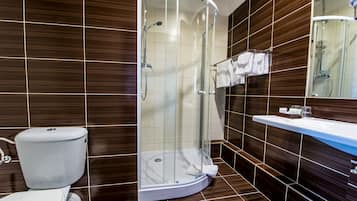 Une salle de bain moderne avec une douche à parois de verre, des toilettes et un lavabo surmonté d’un miroir.