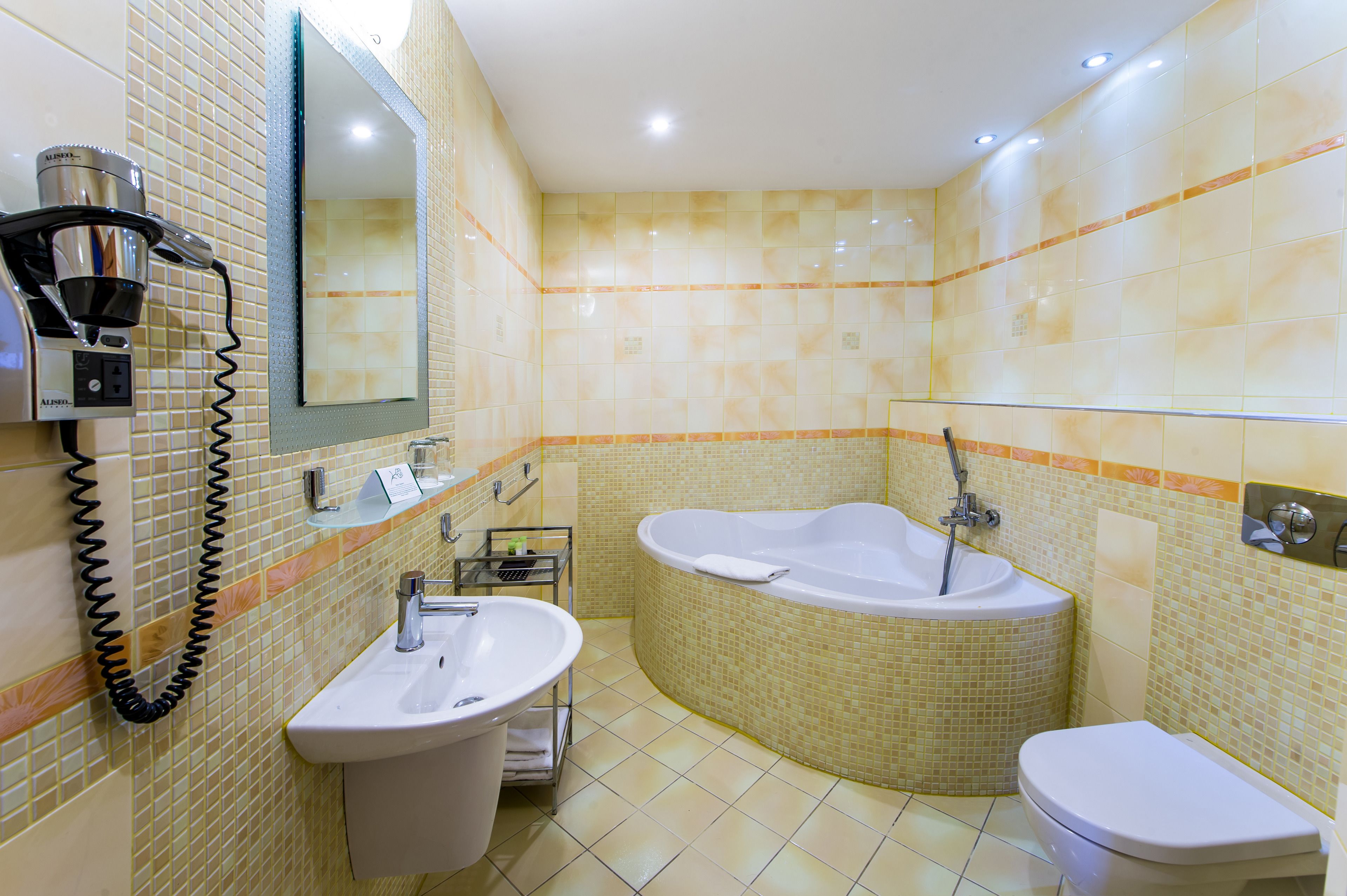 Un baño con lavamanos, espejo y una bañera grande.