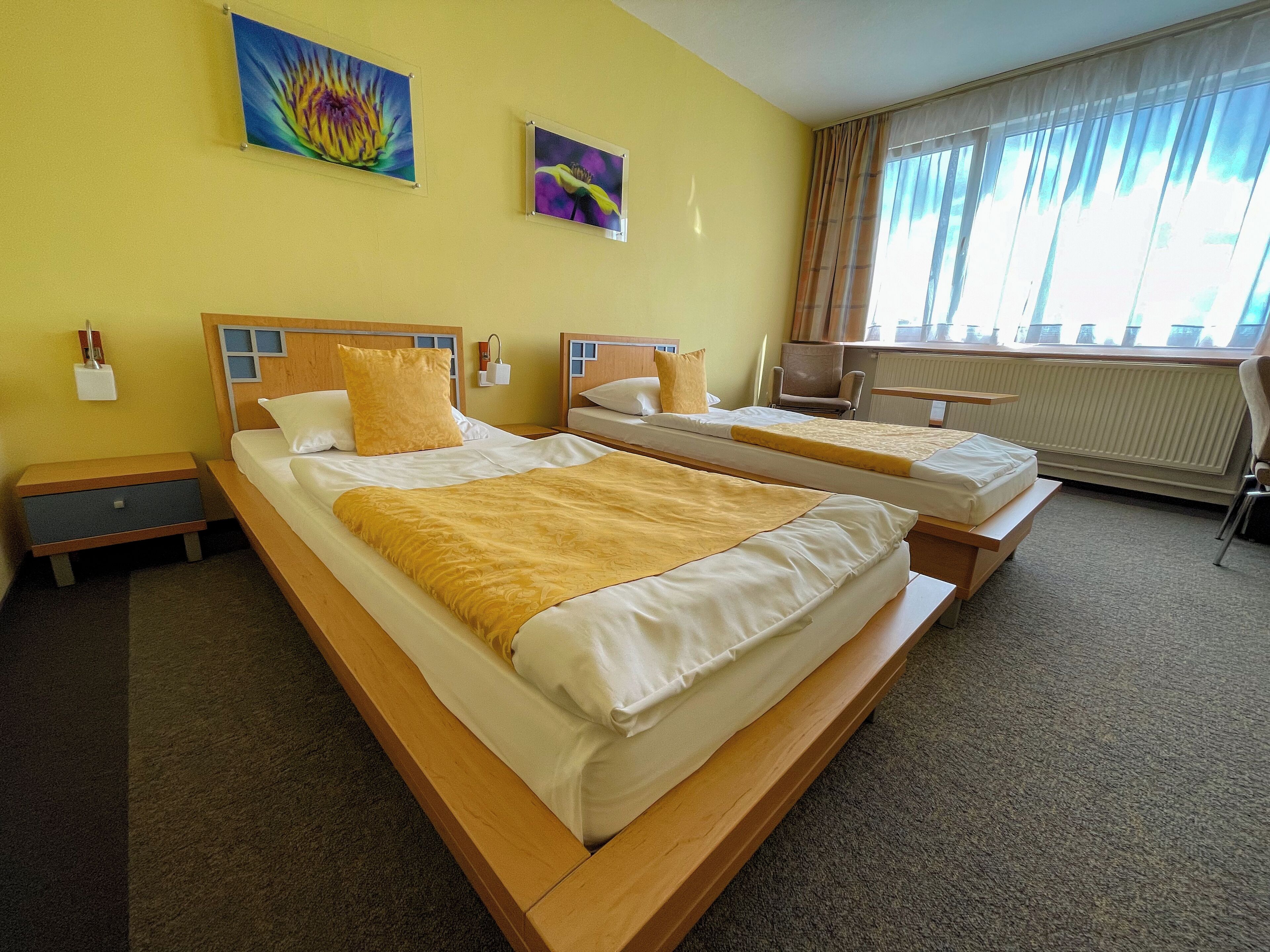 A hotel room with two beds, a desk, a chair, and a window with curtains.