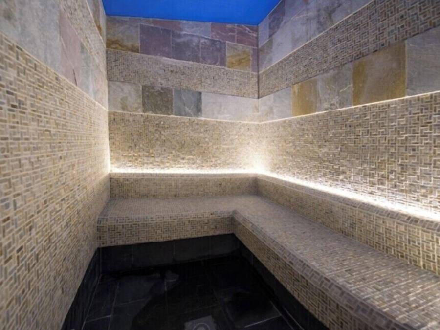 Una habitación con paredes de azulejos y un estampado geométrico, y suelo oscuro.