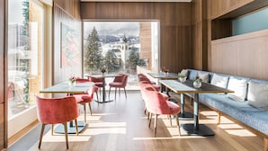 Ett modernt matområde med träpanel, stora fönster och utsikt över ett snötäckt berg.