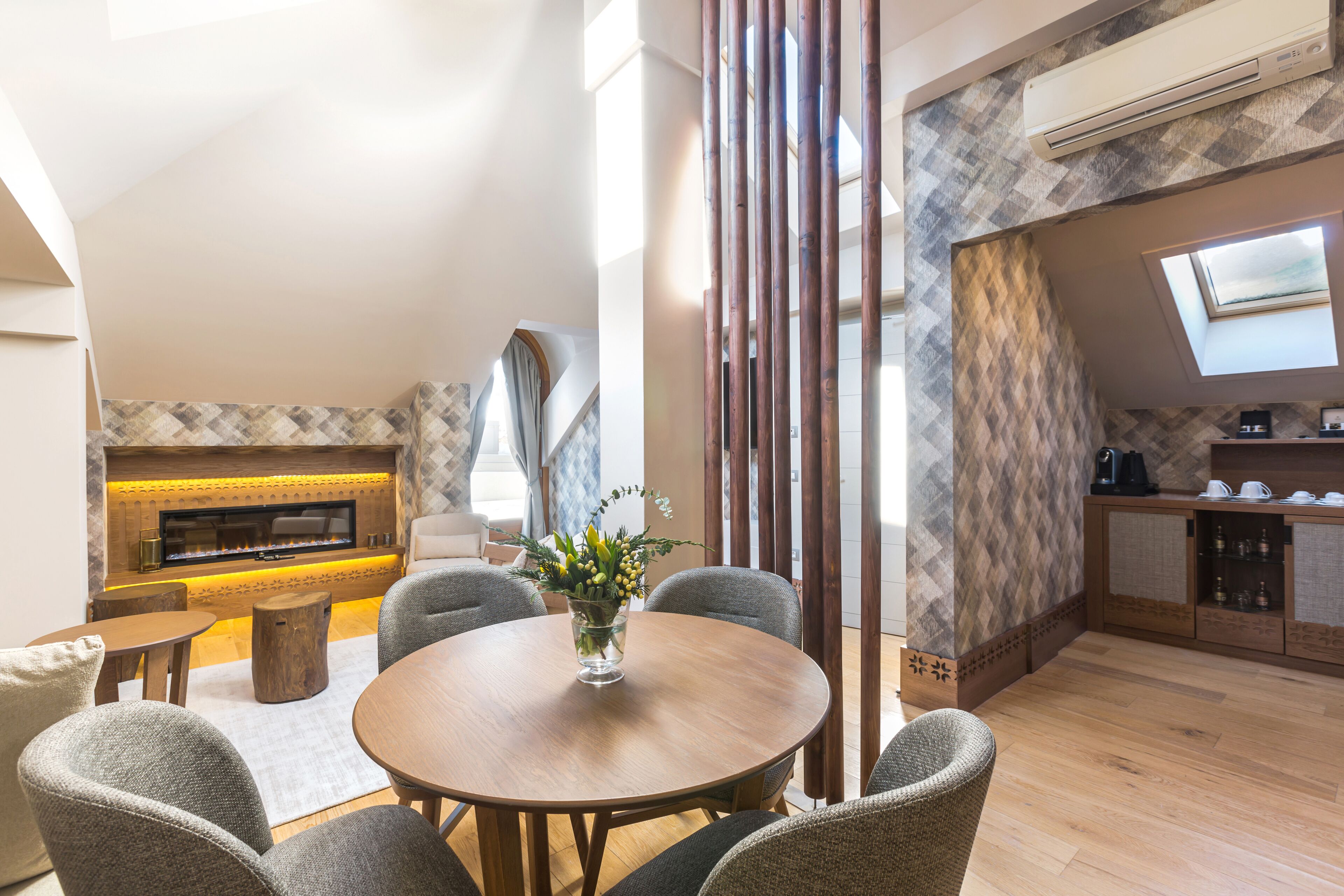 A modern living room with a fireplace, a round dining table, and a kitchen area with a TV.