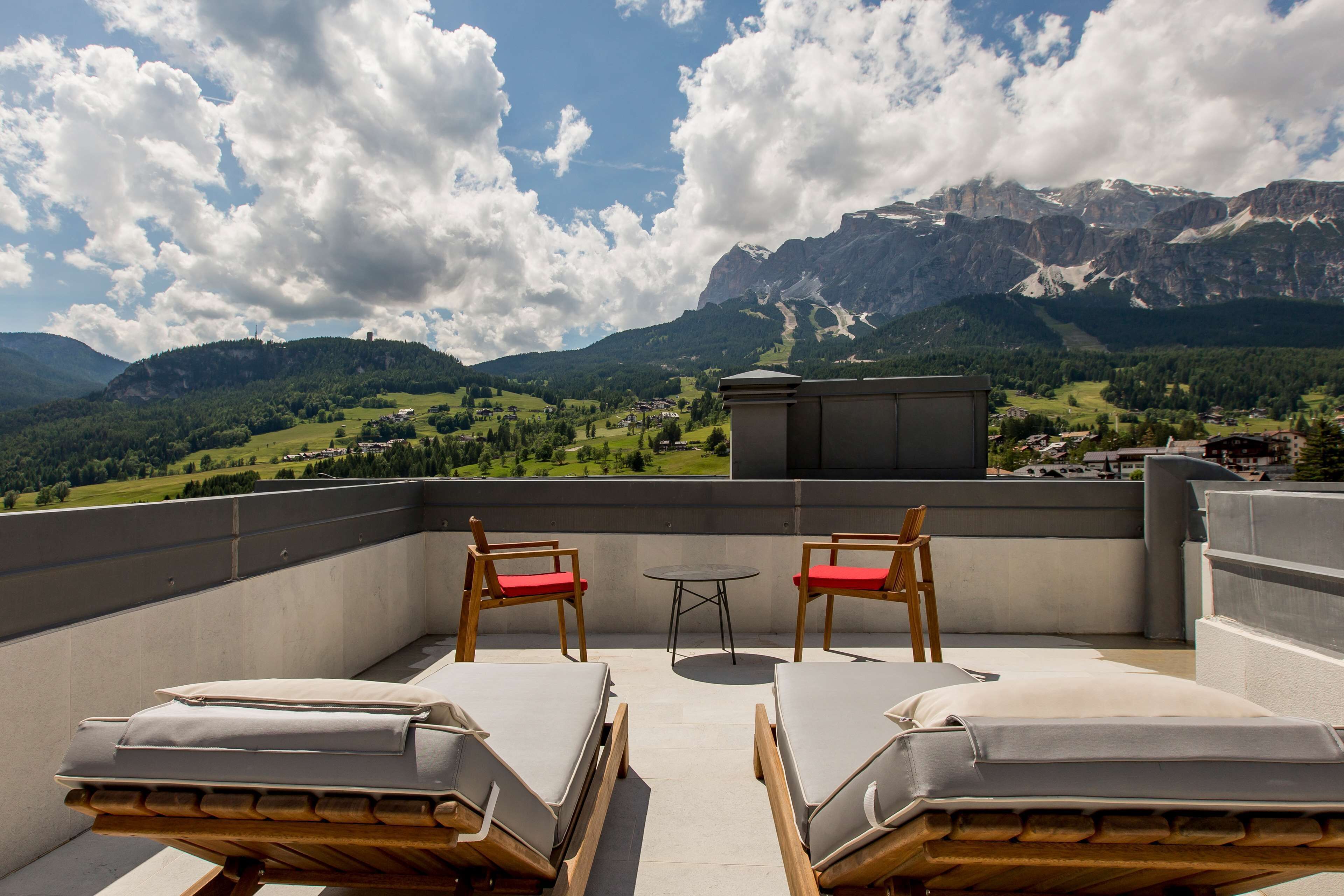 Une terrasse sur le toit, avec deux chaises longues et une petite table, offrant une vue sur un paysage montagneux.