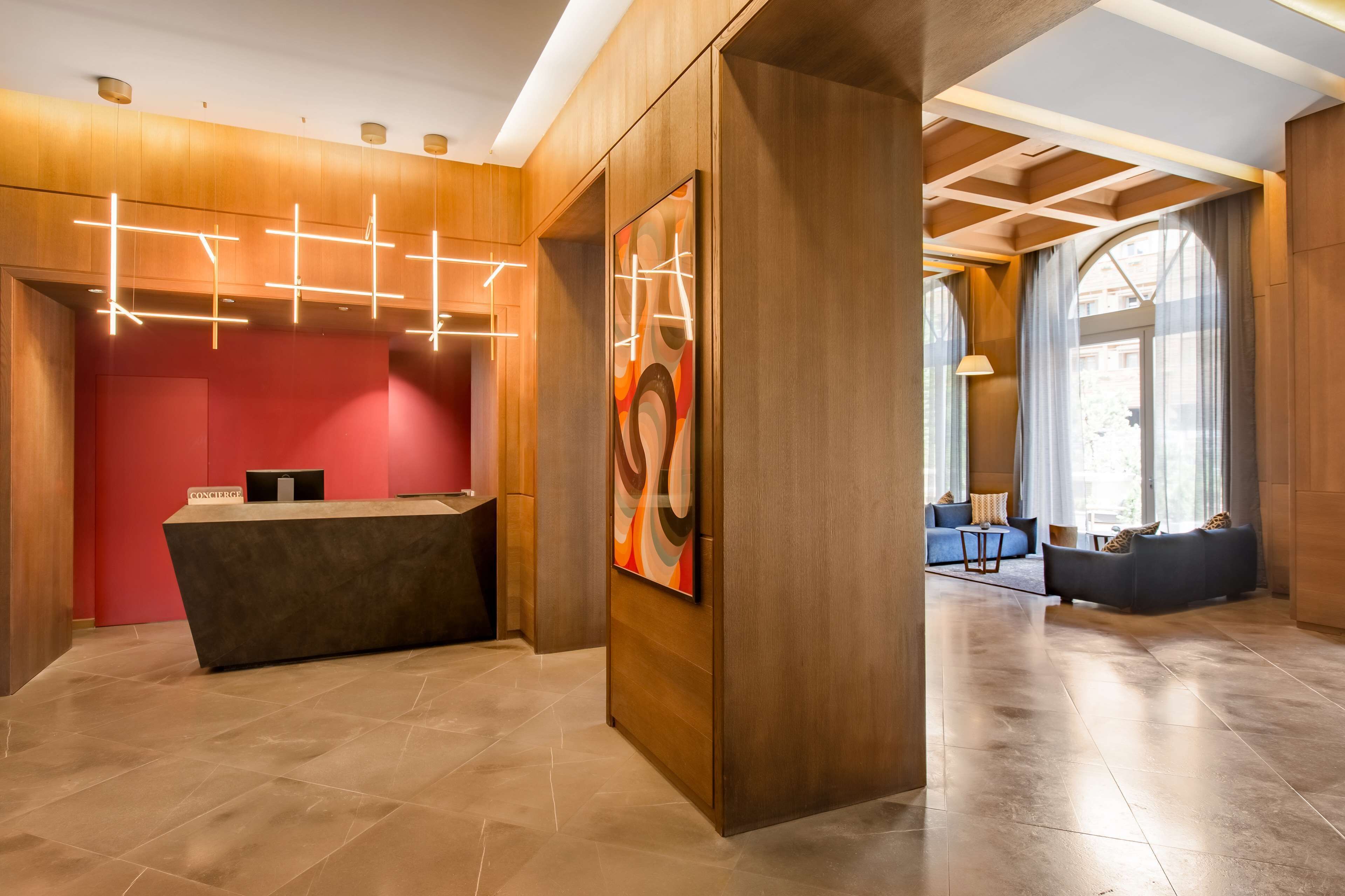 A modern reception area with a wooden reception desk, a large abstract painting, and a seating area with sofas and a coffee table.