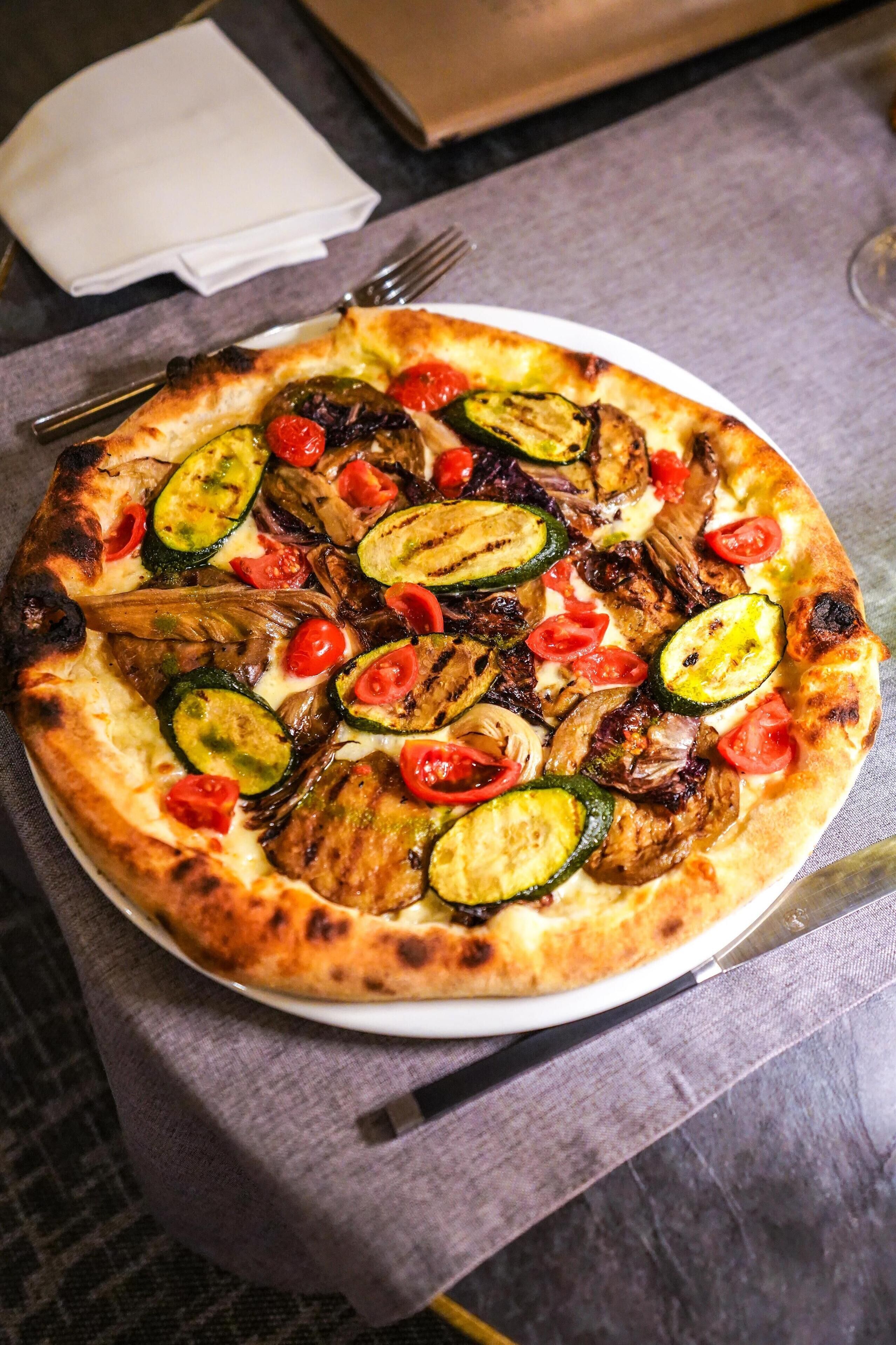Una pizza con diversi ortaggi su un piatto.