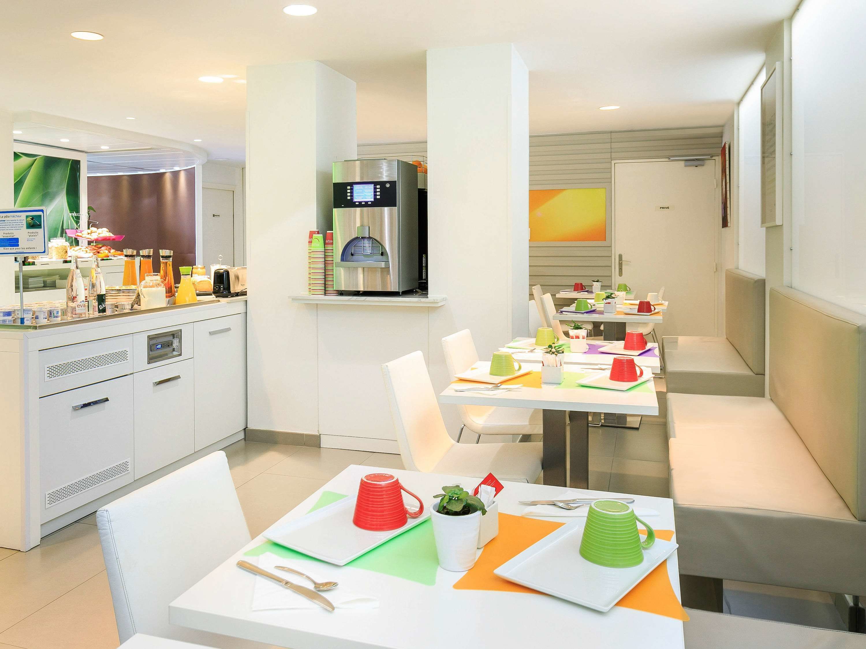 A modern hotel dining area with white tables, chairs, and a coffee machine.