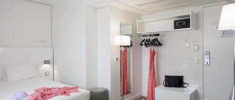 A hotel room with a bed, desk, chair, and a wardrobe.