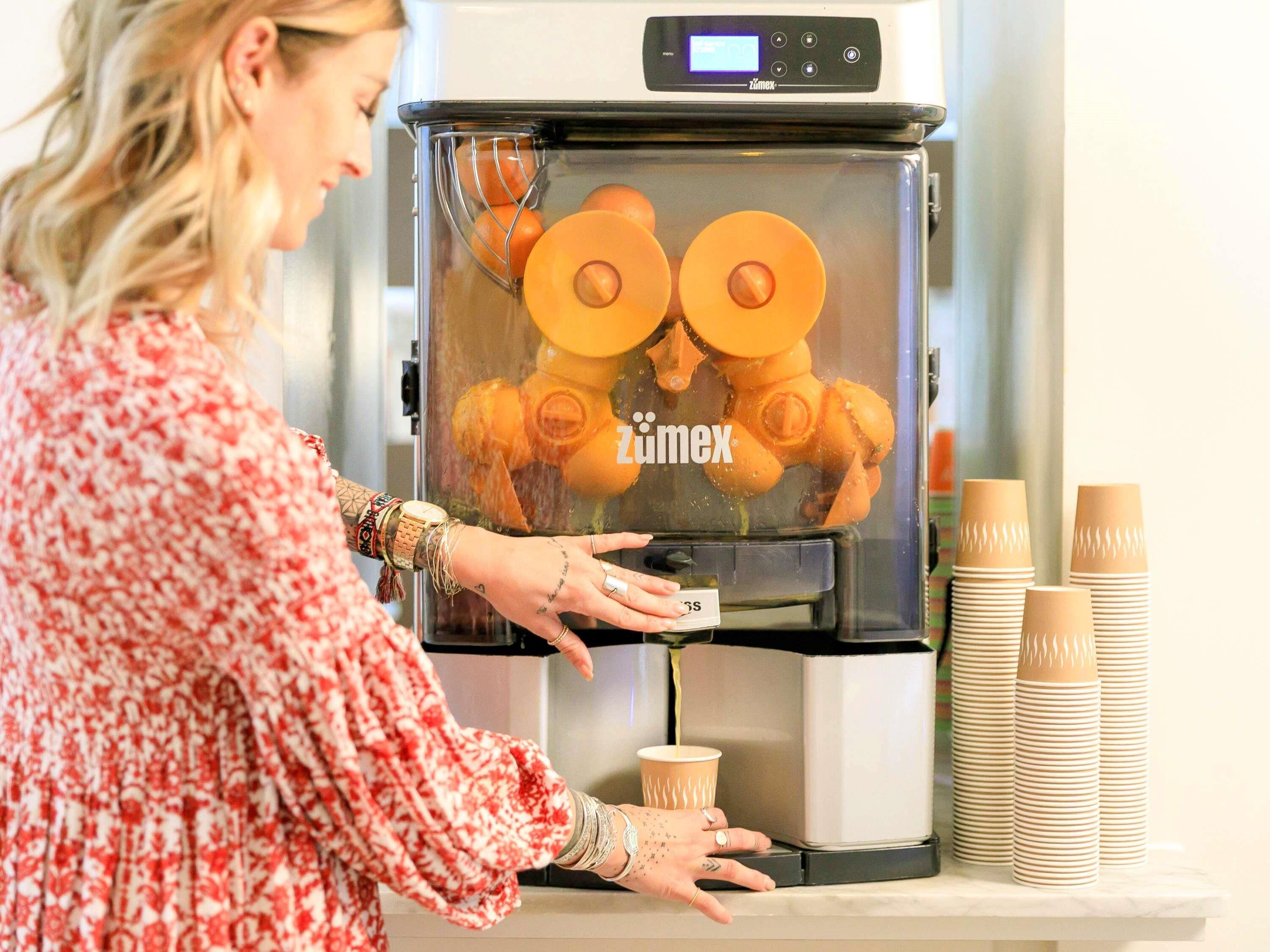 A person operating a coffee machine with a digital display, dispensing coffee into a cup.