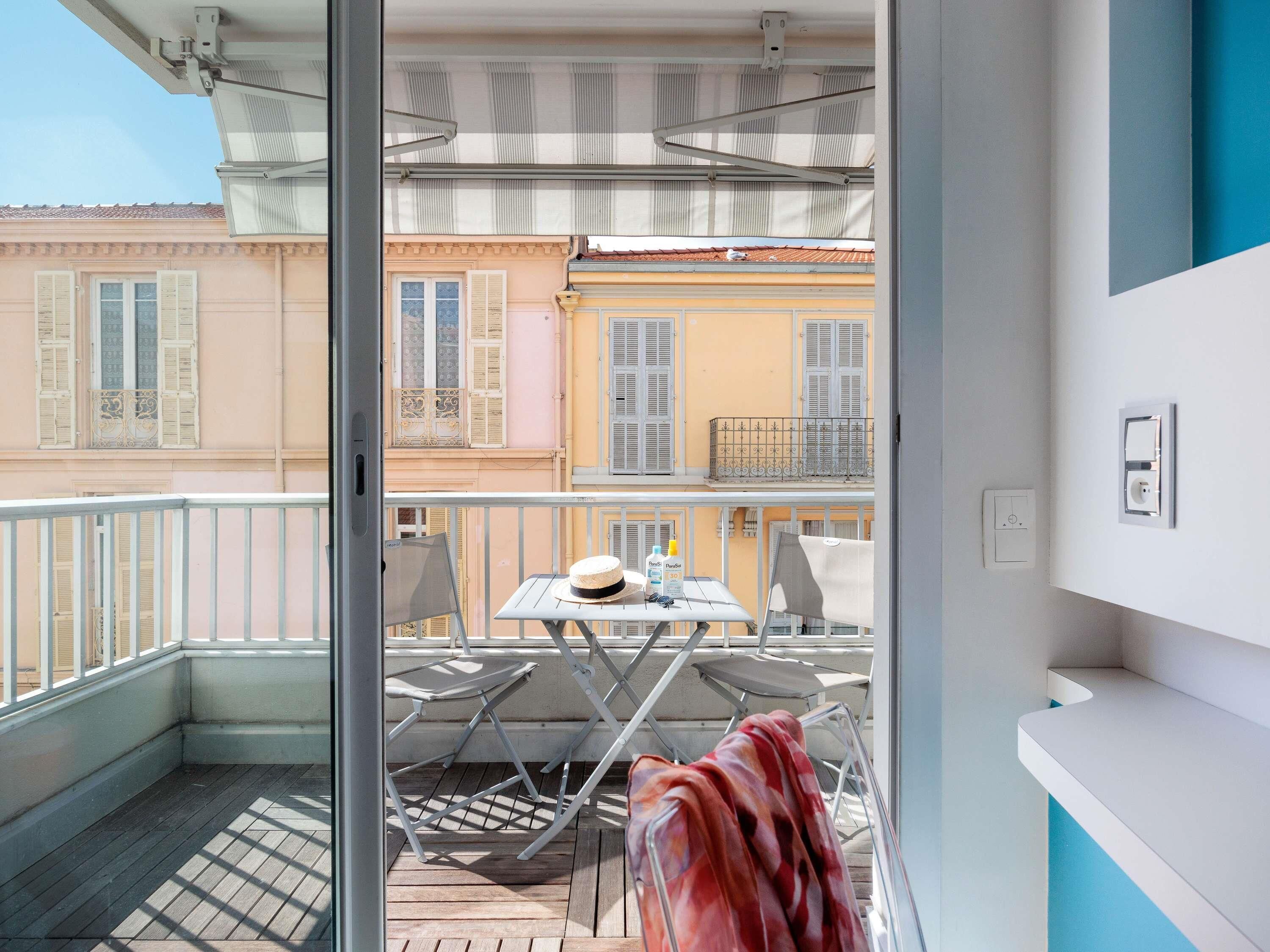 Un balcon avec une table, des chaises et une vue sur les immeubles voisins.