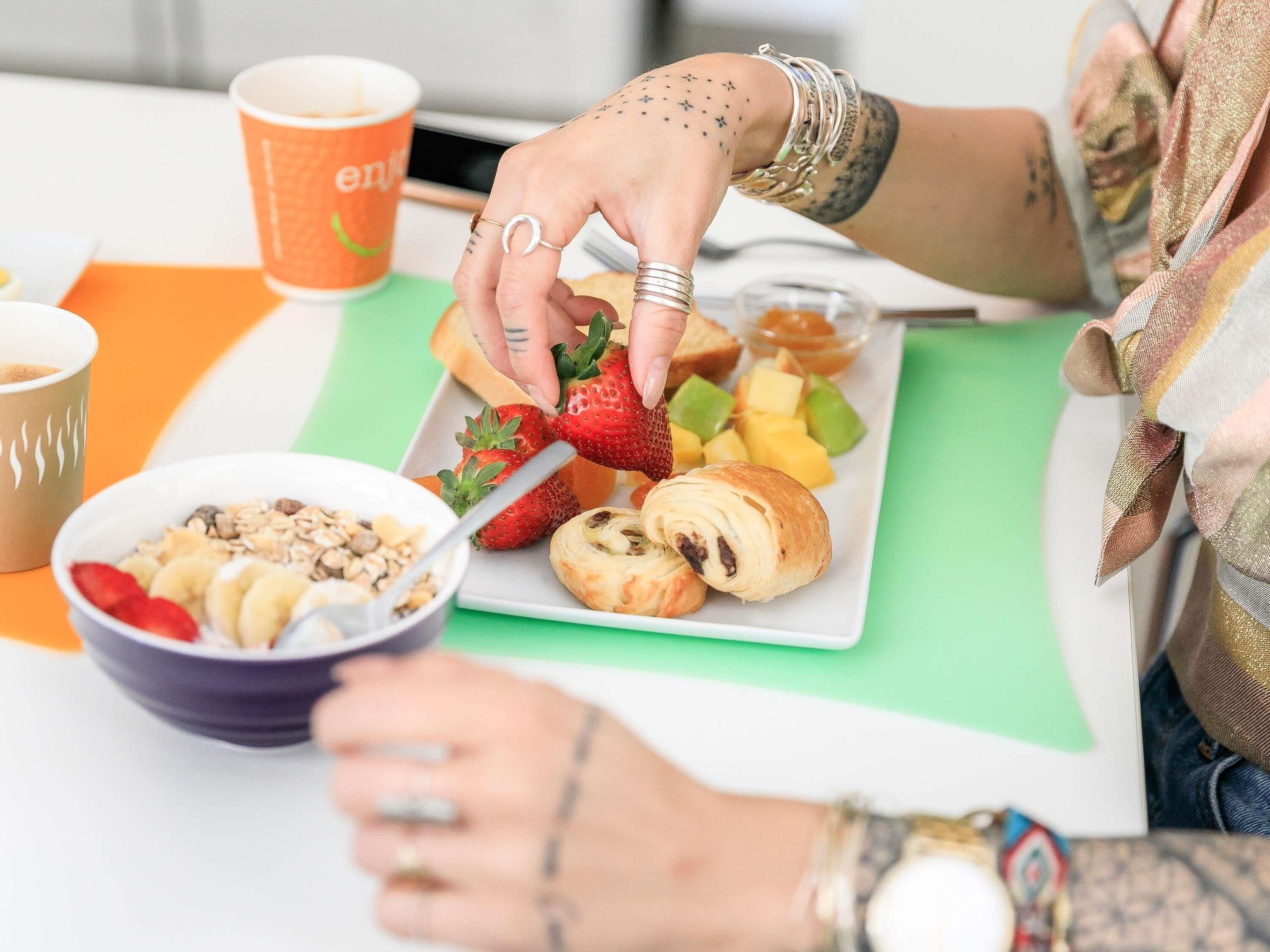 A dining table with a plate of food, a bowl of cereal, and a cup.