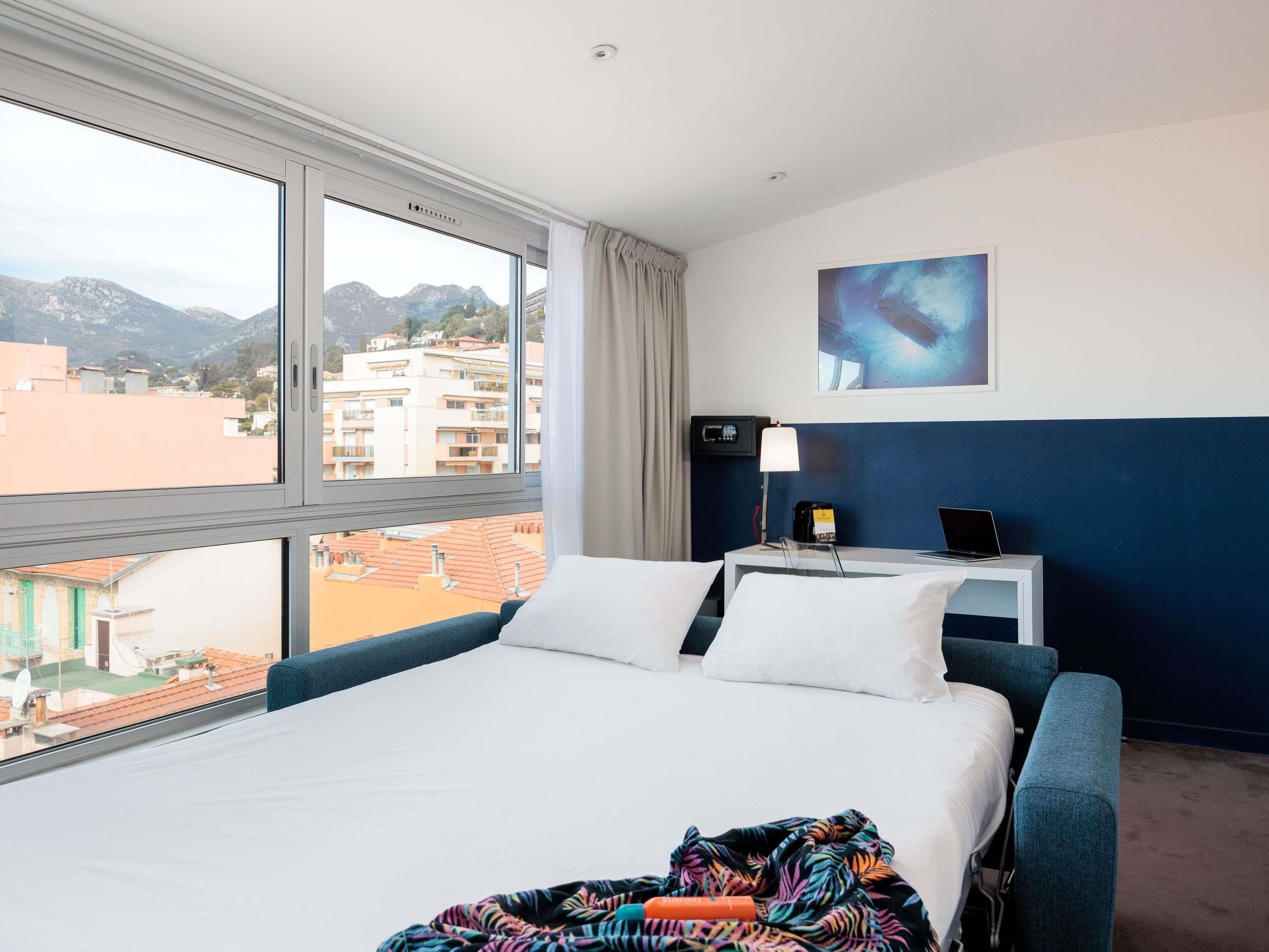 Une chambre d’hôtel avec un lit, un bureau, une lampe et un tableau.