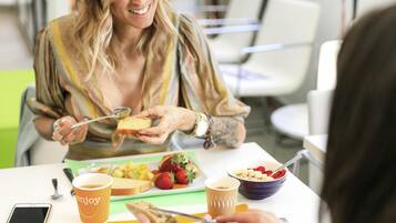 A person eating at a table with a smartphone, a cup, and various food items.