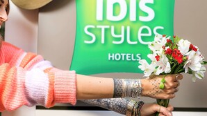 A person holding a bouquet of flowers in front of a sign that reads "ibis Styles Hotels". - ibis Styles Menton Centre (Menton)