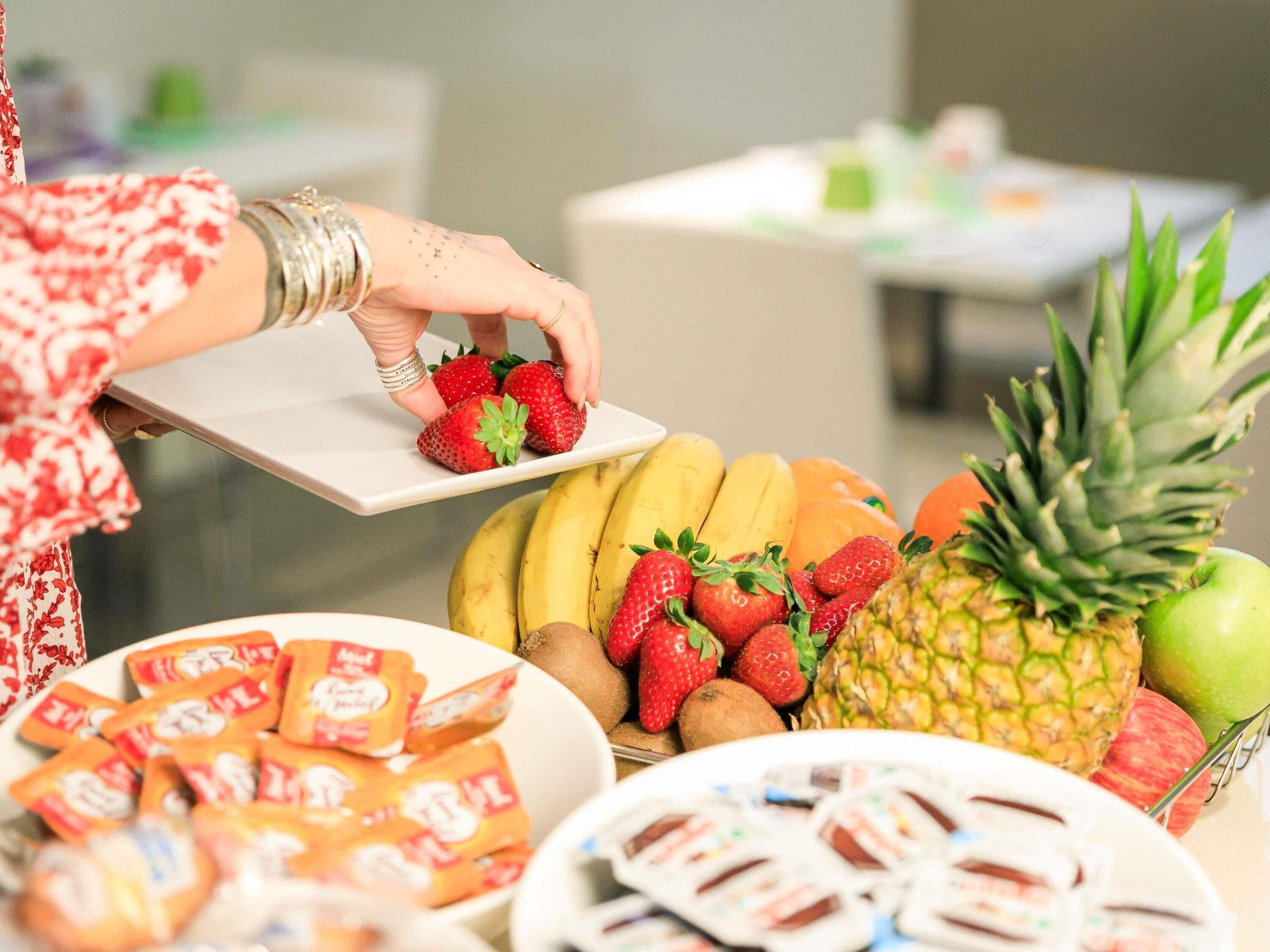 A buffet table with various fruits, a pineapple, and packaged snacks.