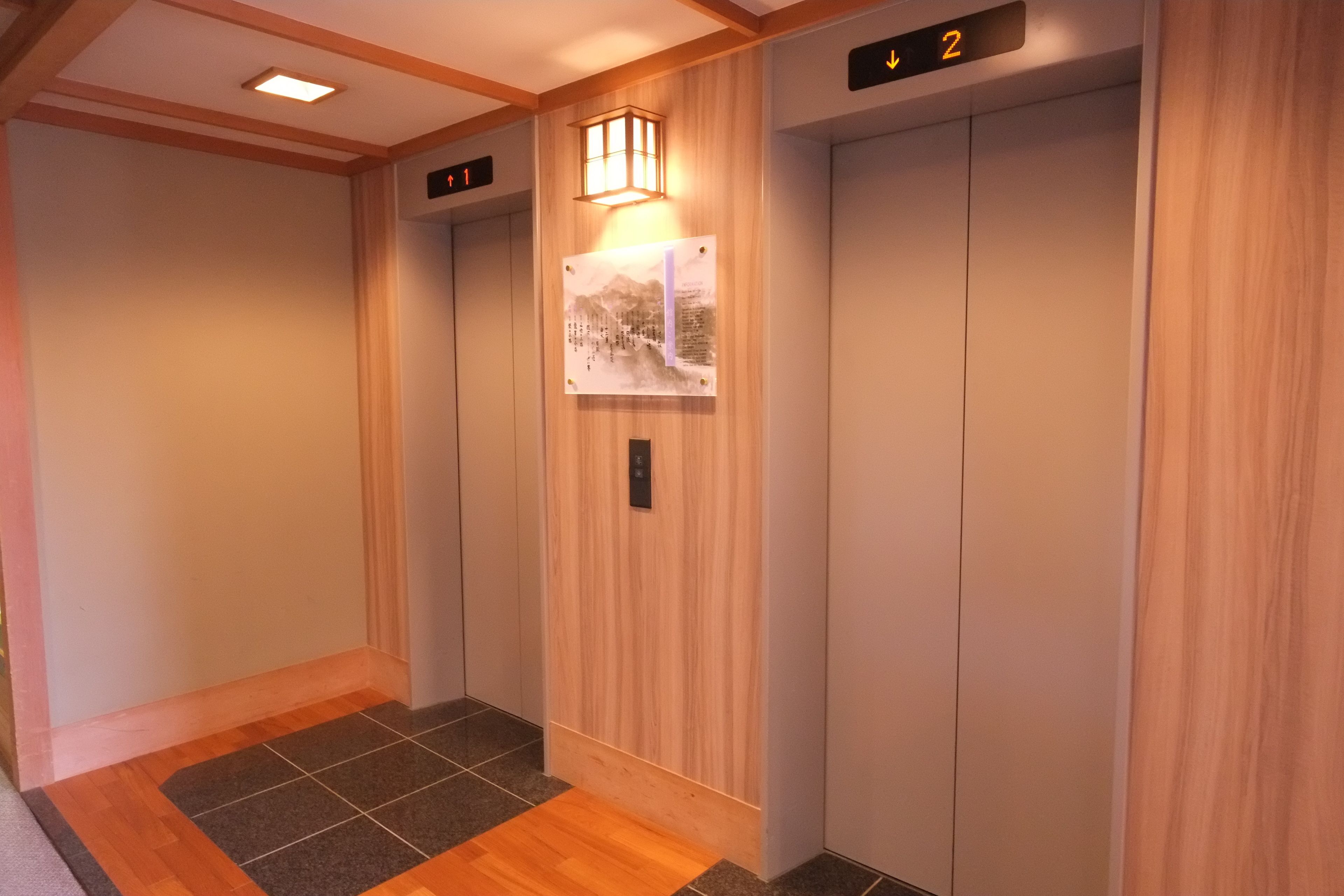An elevator with wooden paneling and a wall-mounted light fixture.