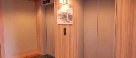 An elevator with wooden paneling and a wall-mounted light fixture.
