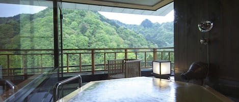 A hot tub with a view of a forested mountain.