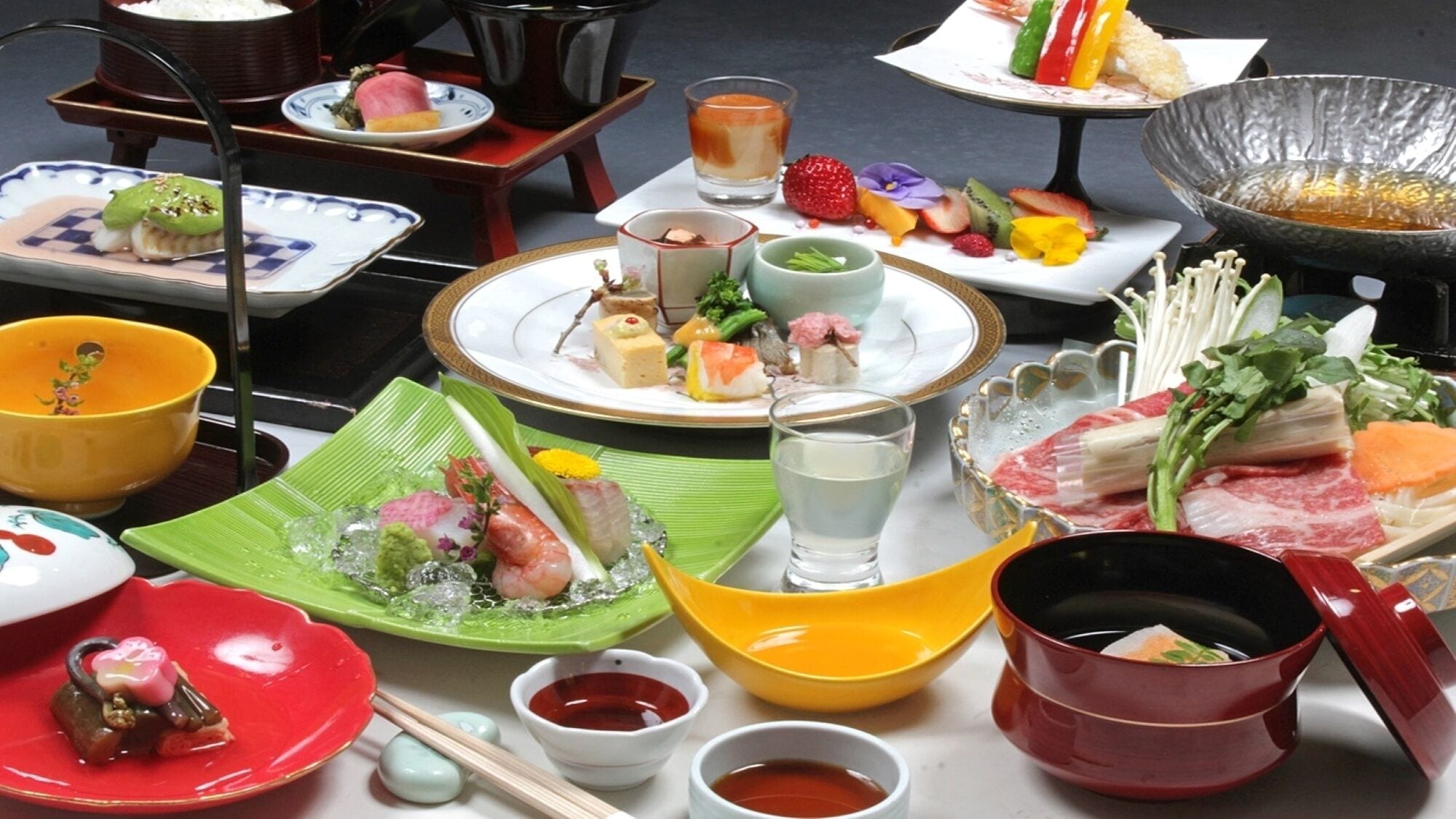 A variety of Japanese dishes and drinks on a table, including sushi, sashimi, and a hot pot.