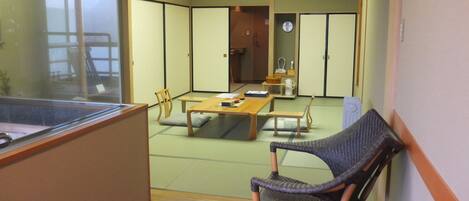 A traditional Japanese room with tatami flooring, low tables, and sliding doors.