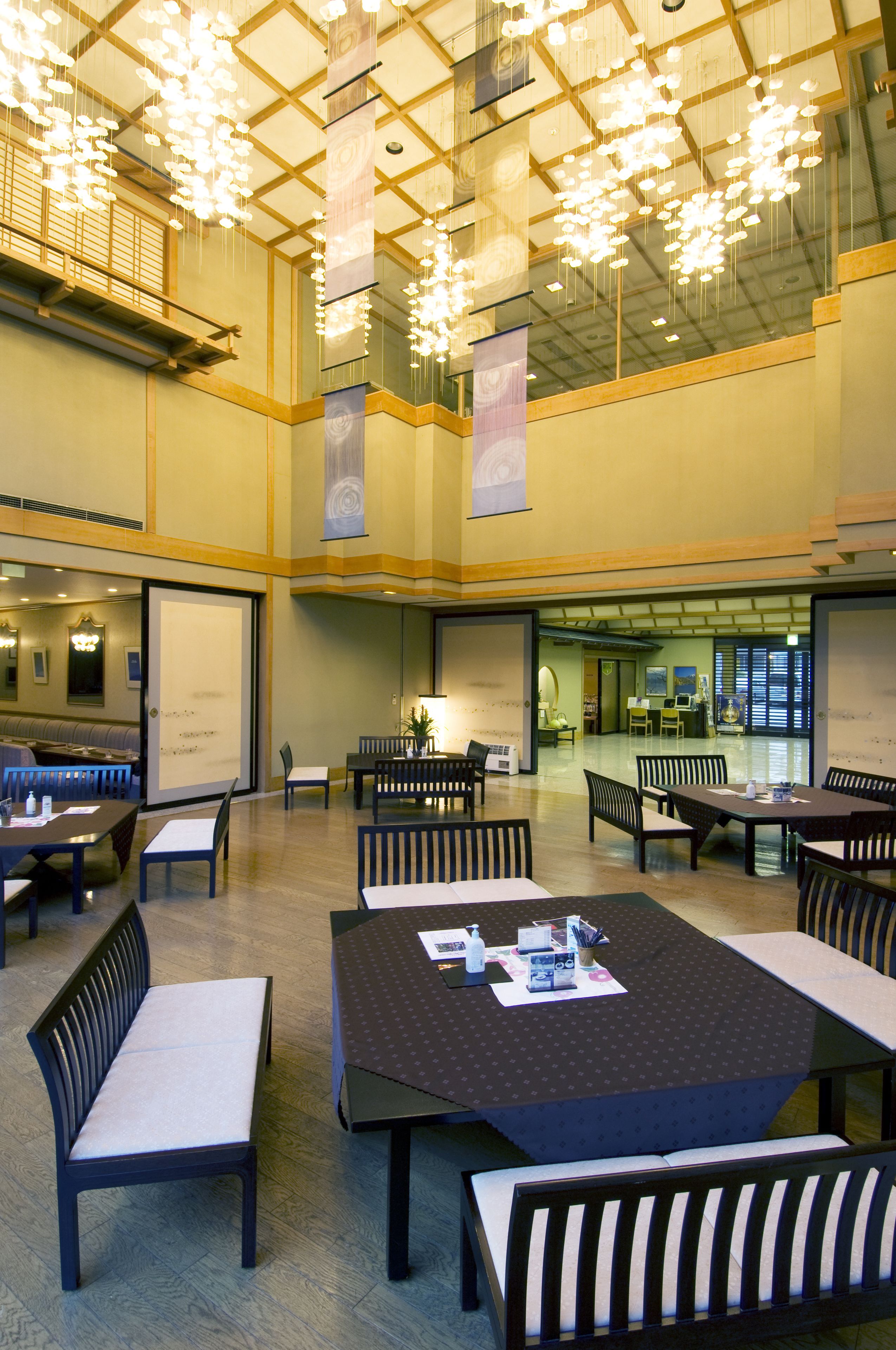 A spacious indoor area with multiple tables and chairs, a whiteboard, and a seating area with a bench.