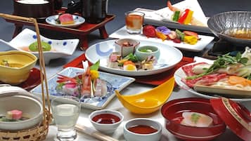 A variety of dishes and drinks on a table, including sushi, sashimi, and a bowl of soup.