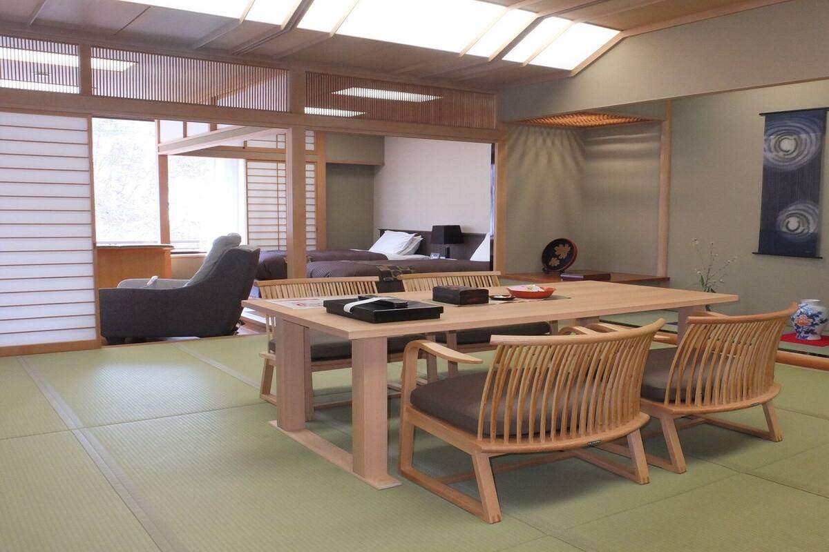 A traditional Japanese-style room with tatami flooring, a low wooden table with chairs, a sofa, and a sliding door.