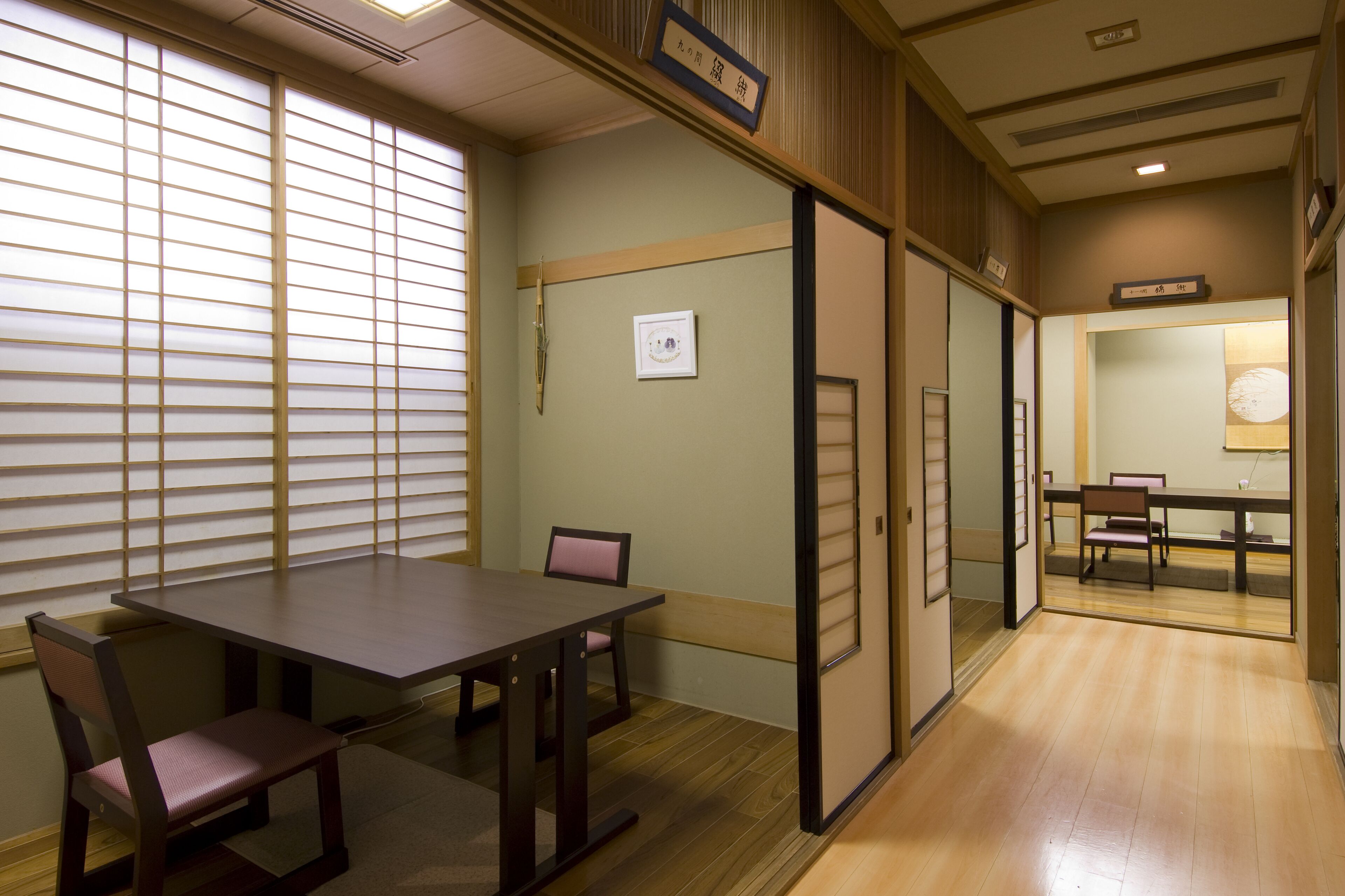 A traditional Japanese room with tatami flooring, a low table with a cushion, and sliding doors.